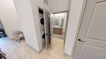 A bathroom with a mirror and a washing machine is visible through an open door.